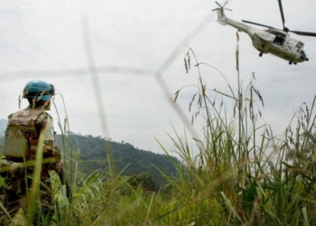A Uruguayan peacekeeper based in Pinga watch as USG Herve Ladsous's helicopter makes its way back toward Goma after a field visit in the area . The town of Pinga was recently deserted by NDC milicia and secured by MONUSCO, the 4th of December 2013.   © MONUSCO/Sylvain Liechti