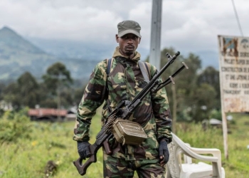 An M23 rebel stands with his weapon during a ceremony to mark the withdrawal from their positions in the town of Kibumba, in the eastern Democratic Republic of the Congo, on Friday, December 23, 2022 [Moses Sawasawa/AP Photo]