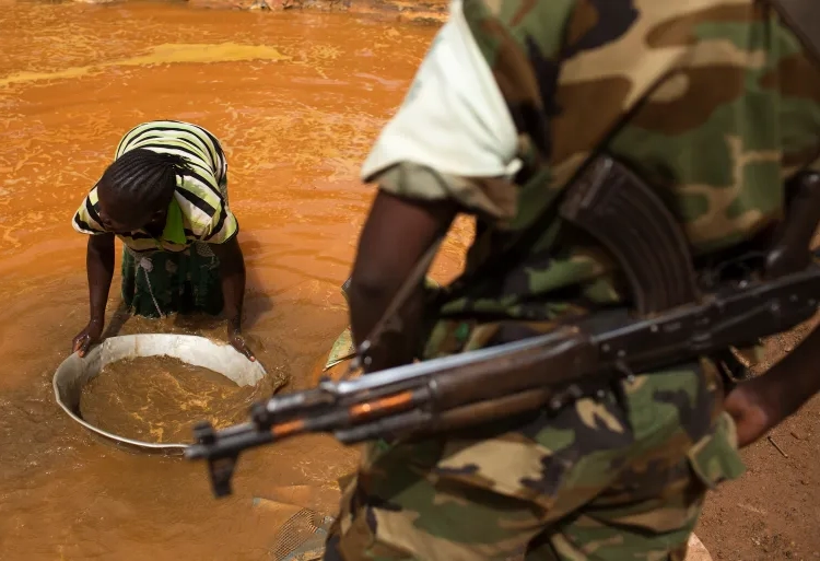 A soldier looks on as a woman pans for gold near an open pit at a mine in Central African Republic [File: Siegfried Modola/Reuters]